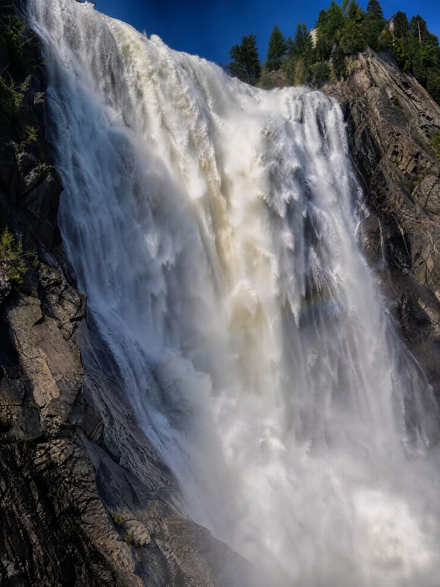 The white column of Montmorency Falls against a dark rock face, seen close up
