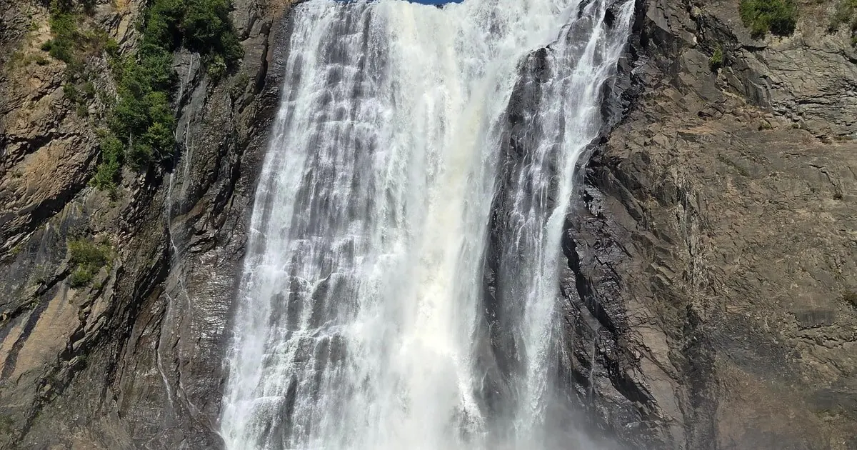 A close view of white water pouring over dark rock at Montmorency Falls